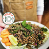 Person holding a plated salad topped with seasoned The Better Butchers Natural plant-based ground and lime wedges.
