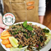 Person holding a plated salad topped with seasoned The Better Butchers Natural plant-based ground and lime wedges.