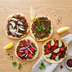 Four plant-based lahmacun flatbreads topped with The Better Butchers ground, red onion, cucumber, tomato, and parsley, served with lemon and sumac