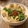 Plant-based chorizo queso dip topped with The Better Butchers Chorizo-style ground, scallions, and cilantro, served with tortilla chips
